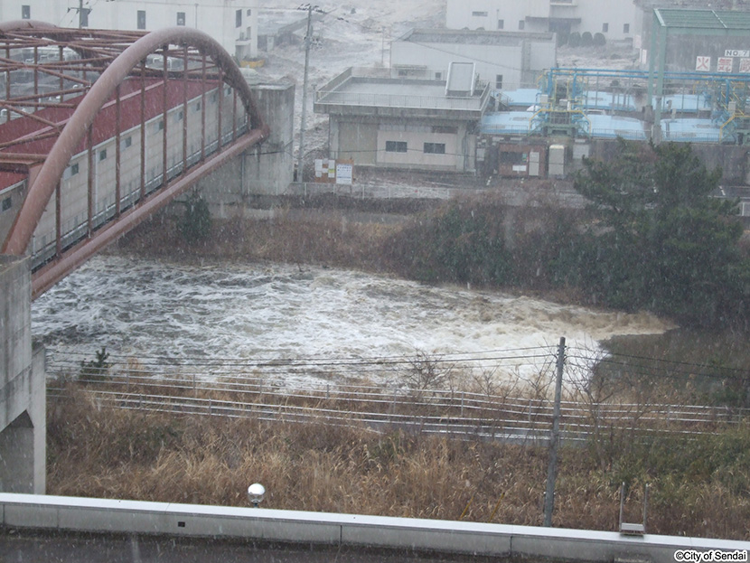 画像：貞山堀に流れ込む津波（南蒲生浄化センター水管橋付近）1