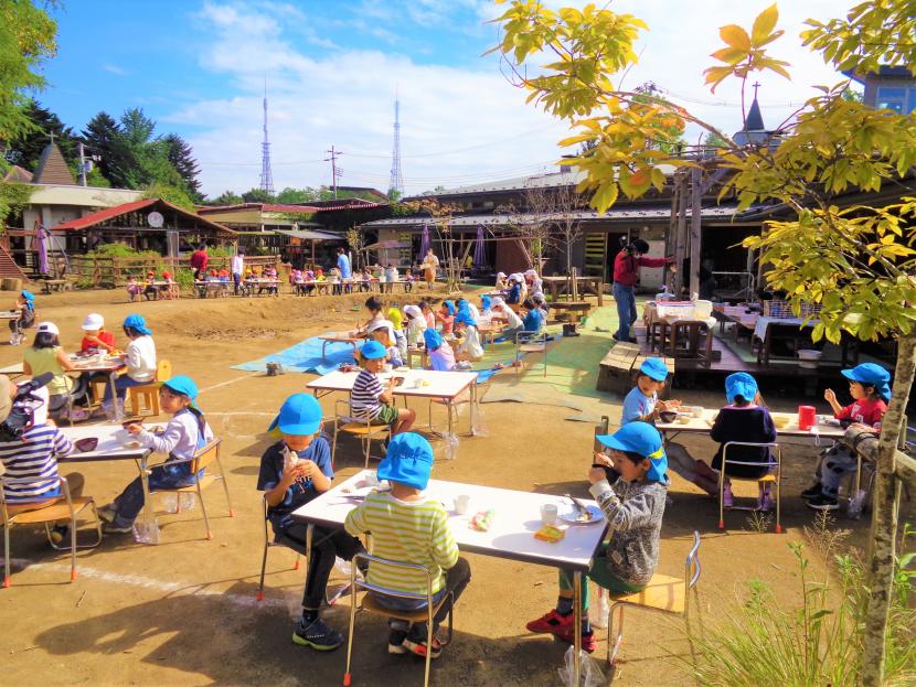 外でさんまを食べる園児たち