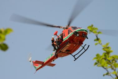 消防ヘリコプターがホイスト装置で救助隊員を降下させている写真