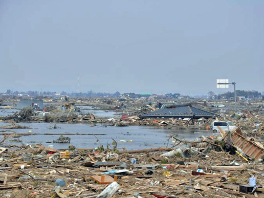 写真：〈種次地区/がれきに埋め尽くされたままの農地〉