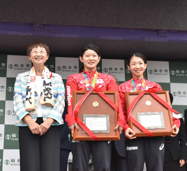 写真：多くの市民の祝福を受け、笑顔を見せる髙橋選手（中央）と松友選手（右）